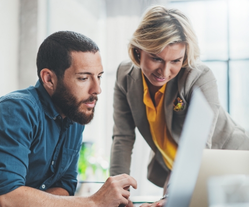 Foto von Mann und Frau die gemeinsam an einem Laptop arbeiten